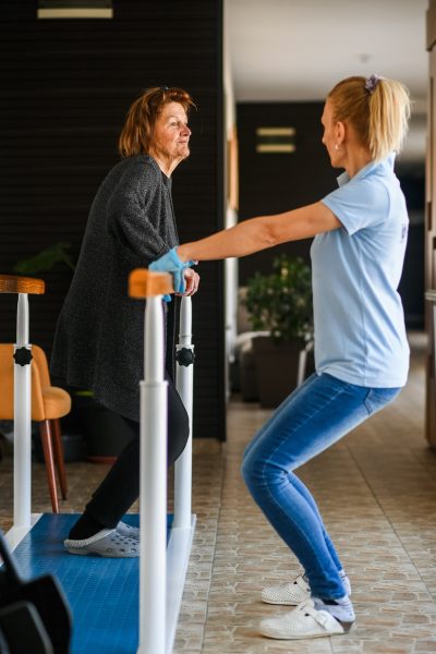 Terapijska šetnja starije žene uz pomoć fizioterapeuta radi oporavka pokretljivosti i stabilnosti